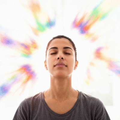 Person visualizing success with eyes closed, serene and focused, surrounded by abstract light and positive energy
